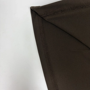 Macro detail of the stitching and sewing craftsmanship on a dark brown bodycon dress