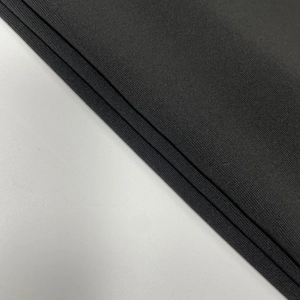 Close-up of the fine knitted fabric texture and soft pleated hem of this black dress