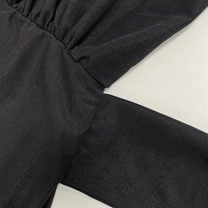 Detailed close-up of black ribbed knit fabric with pleated texture and stitching