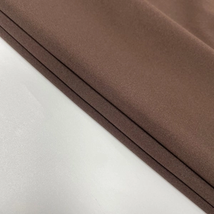 Close-up of deep brown woven fabric showing the dense texture and neat tailoring of the dress