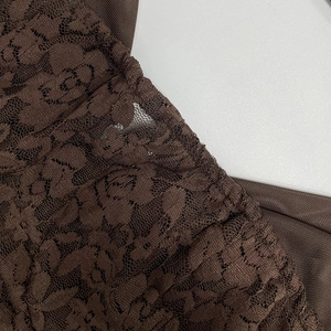 Detail of dark brown floral lace stitching and sheer mesh texture on the bodycon dress