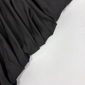 Detailed macro view of black knitted fabric with elegant ruched texture and silky drape