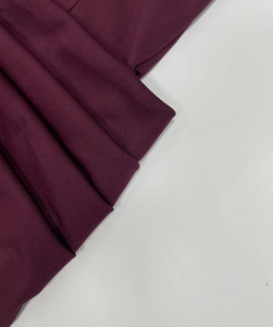 Dettaglio del tessuto plissettato bordeaux che mostra la trama dell'abito con scollo a V