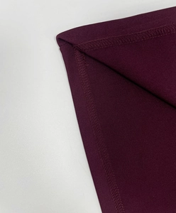 Dettaglio del tessuto viola scuro con cuciture premium e materiale a maglia testurizzato