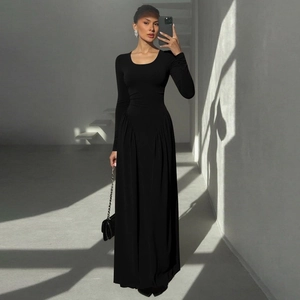 Close-up of elegant pleated hem detail on a black long-sleeved French style maxi dress