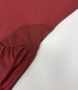 Detailed macro view of the ruched side and diamond mesh panel on the burgundy dress