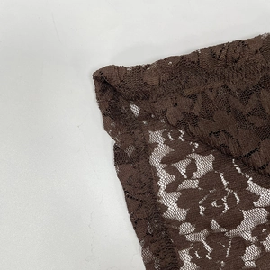 Detailed macro view of brown lace floral pattern and neat double-needle stitching on dress