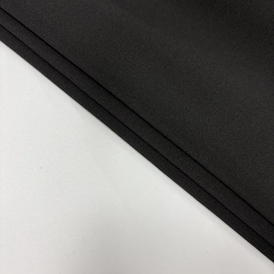 Close-up detail of high-density black knitted fabric showing fine ribbed texture and soft drape