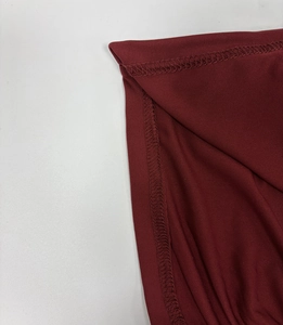 Detailed close-up of overlock stitching and smooth wine red fabric on the mini dress