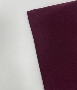 Dettaglio di un abito bordeaux con doppie cuciture precise e trama fine della maglia