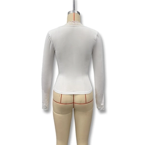 Détail du haut blanc ajusté à manches longues avec dentelle délicate sur le col et les poignets