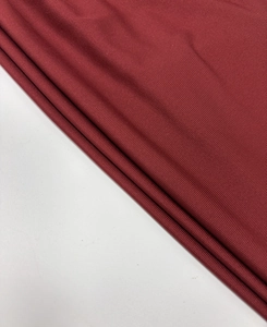 Close-up of burgundy ribbed knit fabric showing detailed vertical texture and elasticity