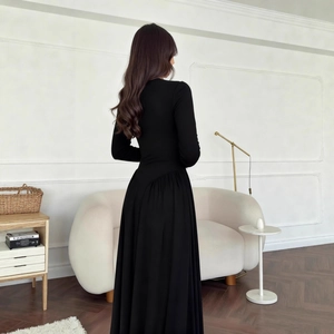 Rear view of a black long-sleeved dress showing elegant pleated waist and flowing skirt detail