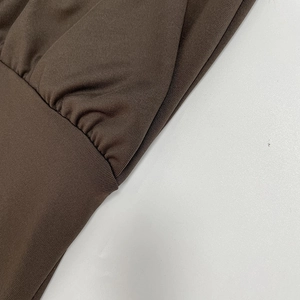 Dettaglio dell'abito in maglia color caffè scuro con pieghe sottili e trama a costine