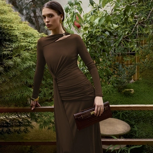 Détail d'une robe marron à manches longues avec décolleté torsadé ajouré et plis à la taille