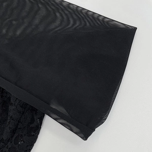 Close-up of intricate floral lace embroidery and fine black mesh texture on a slim dress