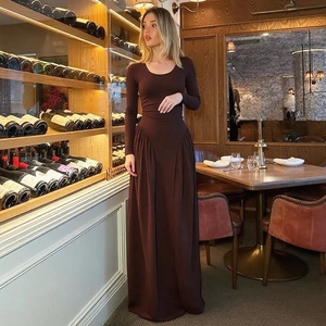 Detail view of the fine pleats and flowing fabric of this deep brown long maxi dress