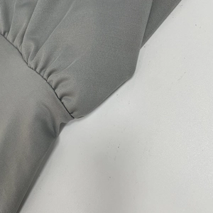 Vista macro del tessuto grigio a costine e dettagli arricciati in vita del vestito