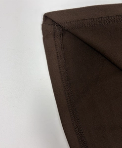 Gros plan détaillé de la couture surjet sur un tissu en maille marron foncé de qualité