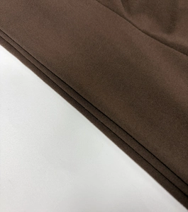 Gros plan du tissu tricoté marron foncé montrant la texture dense et l'ourlet élastique