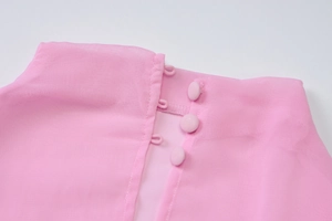Close-up of pink chiffon dress neckline with three delicate fabric buttons and fine stitching