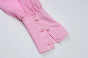 Detail of pink chiffon long sleeve cuffs with fabric-covered buttons and pleated texture