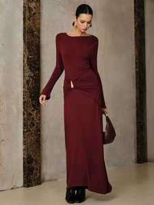 Close-up of elegant asymmetric waist pleats with a gold metal buckle on a burgundy dress