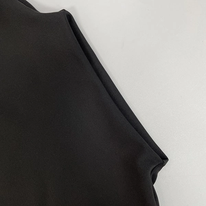 Detail of premium black knit fabric with precise stitching on neck edge and sleeve cuff