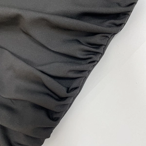 Close-up of ruched detail and elastic knit fabric on a black long sleeve dress