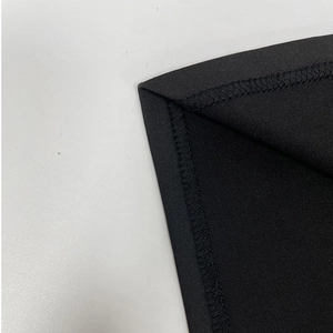 Detailed view of overlock stitching and knit texture on black long sleeve dress hem