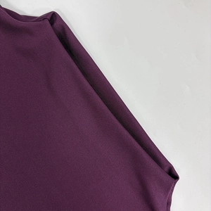 Close-up of deep purple ribbed knit fabric texture on long sleeve dress details