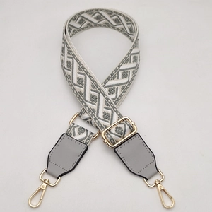 Detail of adjustable gray geometric woven shoulder strap with gold metal lobster clasps