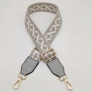 Close-up of adjustable wide woven bag strap with grey geometric pattern and gold hardware