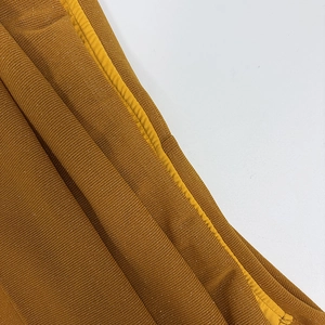 Close-up detail of mustard mesh fabric with silver glitter shimmer and clean seams.