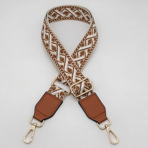 Detail of adjustable wide jacquard bag strap with vintage geometric patterns and gold clips