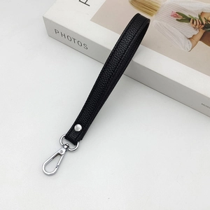 Black lychee pattern leather wristlet strap with silver metal clasp on white background