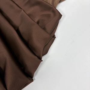 Détail du tissu satiné marron foncé élégant avec texture lisse et drapé brillant