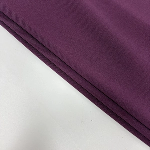 Detailed view of dark purple knit fabric texture with elegant pleated drape details