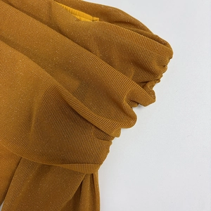 Detail of ochre mesh fabric with metallic glitter threads and elegant ruched textures