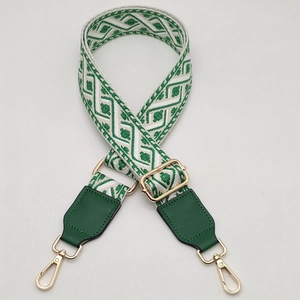 Close-up of green and white geometric woven wide strap with gold-tone hardware and leather ends