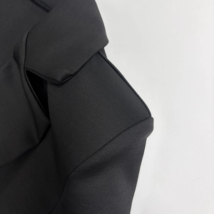 Detail of a black bodycon dress showing the crisp lapel and shoulder tailoring with a smooth texture