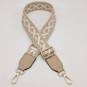 Detail of adjustable geometric jacquard bag strap with golden metal swivel hooks and leather