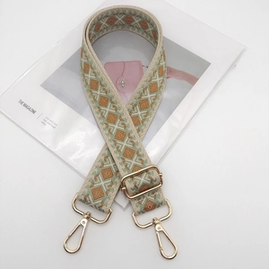 Detail of adjustable geometric patterned bag strap with premium gold metal hooks
