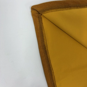 Close-up of overlock stitching and knit fabric texture on a yellow off-shoulder dress