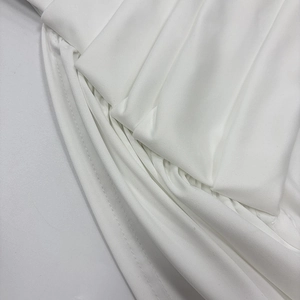Detailed macro view of pure white dress featuring elegant pleated texture and clean stitching