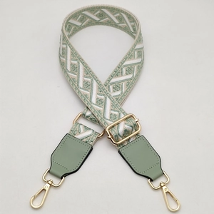 Detail of green geometric woven bag strap with adjustable gold buckle and swivel clasp
