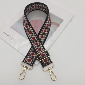 Detailed view of adjustable crossbody bag strap with red and black geometric diamond patterns