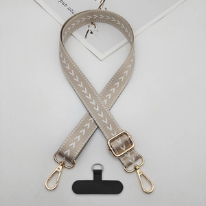 Macro detail of beige woven phone lanyard strap with golden metal clasp and black tether tab