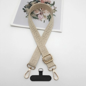 Detail of woven phone strap with golden metal clips and beige geometric patterns