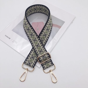 Close-up of green and white diamond pattern wide woven bag strap with gold metal buckle